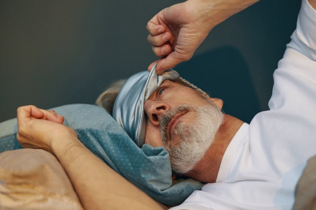 Man met slaapmasker wordt wakker met verstopte neus en vermoeide blik, mogelijk door huisstofmijtallergie.